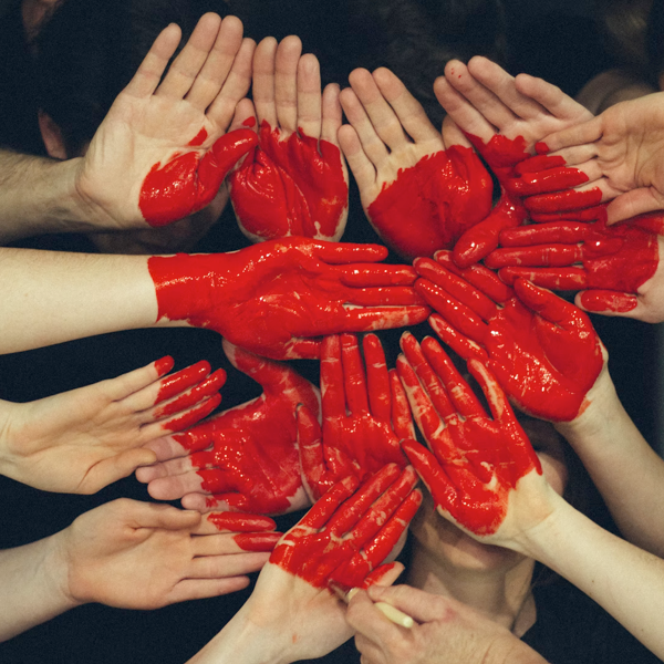 Several hands painted with red paint in the shape of a heart